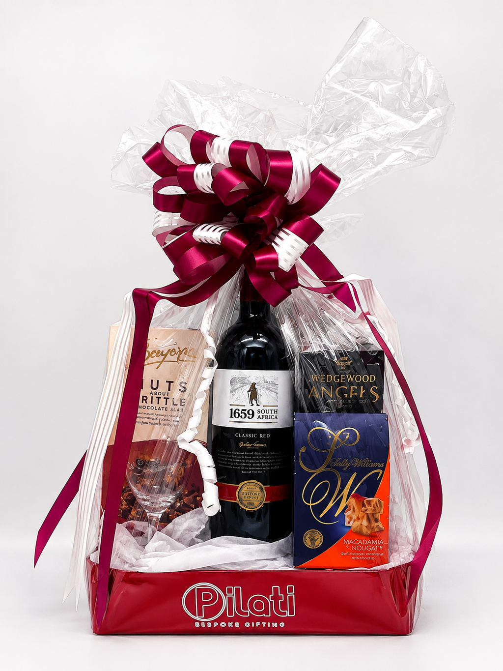A Pilot gift basket containing a bottle of wine, with a large red and white bow, on a white background.