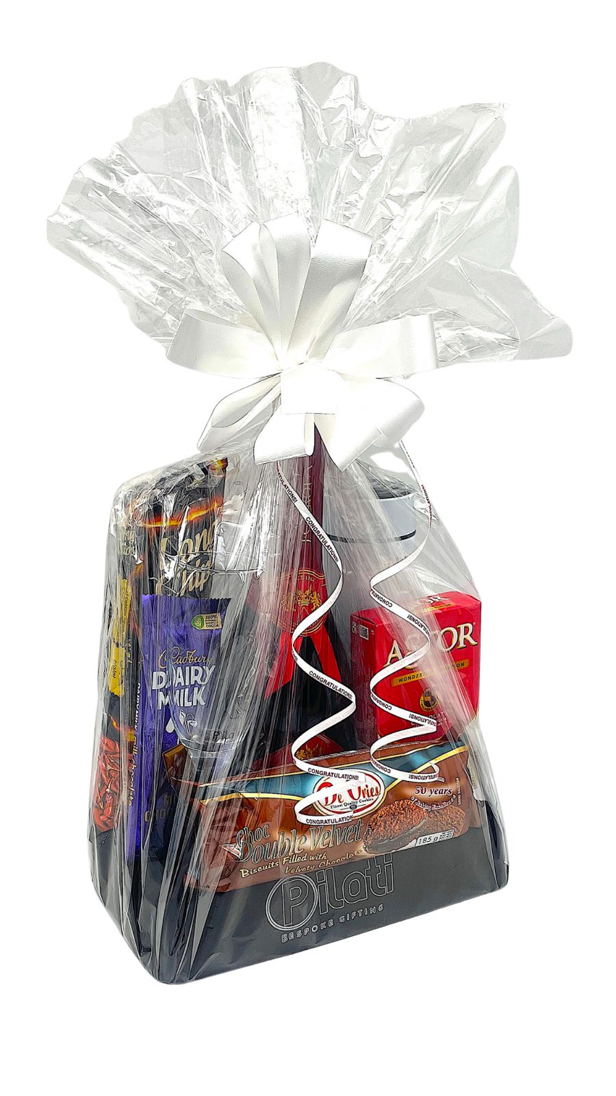 A gourmet gift basket filled with assorted chocolates, snacks, and treats, wrapped in clear love and tied with a white ribbon bow, set against a plain white background.