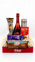 A Pilati branded gift basket containing  a bag of Long Chips, a box of Astor, a chocolate bar, arranged in a red basket with white filler on a white background.